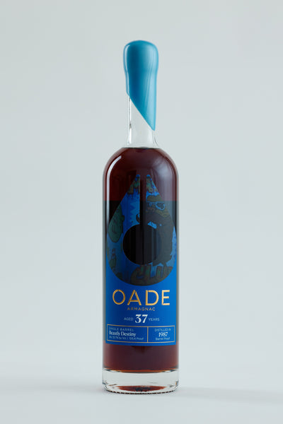 Bottle of OADE Armagnac with blue label on a light gray background