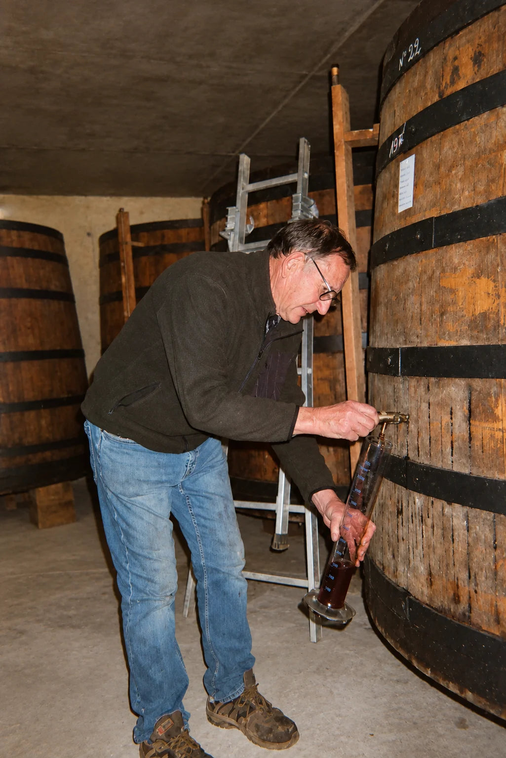 Drawing an Armagnac sample from a large oak cask at Domaine de Juglaron near Eauze, France.